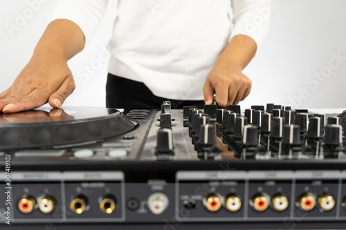 Hands of DJ mixing tracks on professional sound mixer.Fashionable rings on fingers of girl disc jockey playing music.Closeup,knobs and regulators in focus.Girl dj play music tracks at house party © Gayan