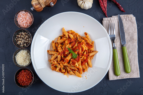 Penne pasta with chili sauce arrabiata. Classic italian penne arrabiata with basil and freshly grated pecorino cheese on a rustic wooden table. photo