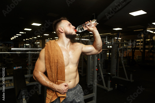 Sports handsome man drinking water after the raining in the empty gym.