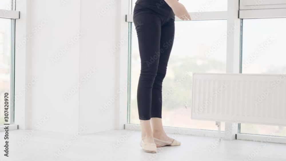 girl dancer practicing dance movement legs on a floor in white studio