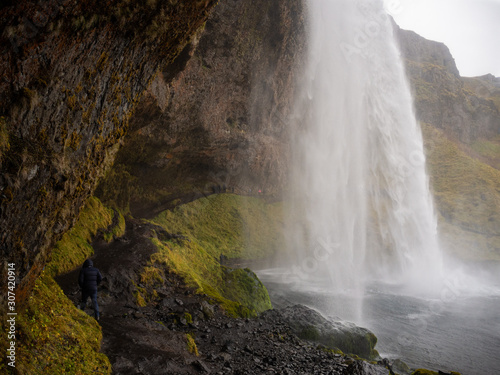 The slippery pathway behind the water curtain of the impressive Seljalandsfoss waterfall. South Coast of Iceland.