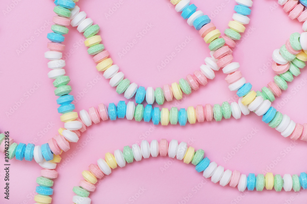 Candy necklace on pink pastel colored background.