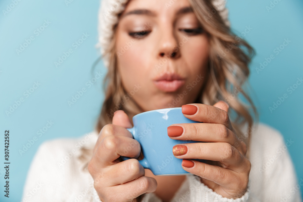 Portrait of blonde attractive woman blowing and holding cup Portrait of blonde attractive woman blowing and holding cup