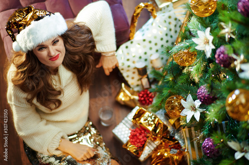 woman under decorated Christmas tree near present boxes