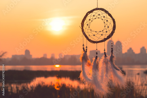 Dream catcher against the background of the present in the form of a city in the background, and the future in the foreground. Refusal of city vanity. Downshifting Philosophy photo