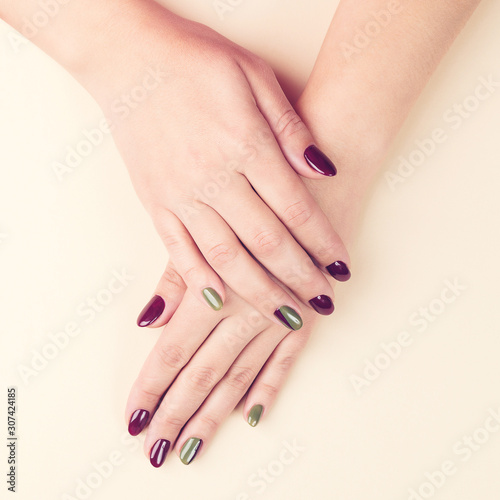 Female hands with creative manicure. Beautiful woman hands on beige background  top view. Manicured nails concept