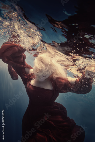 Portrait of a woman in a red dress underwater