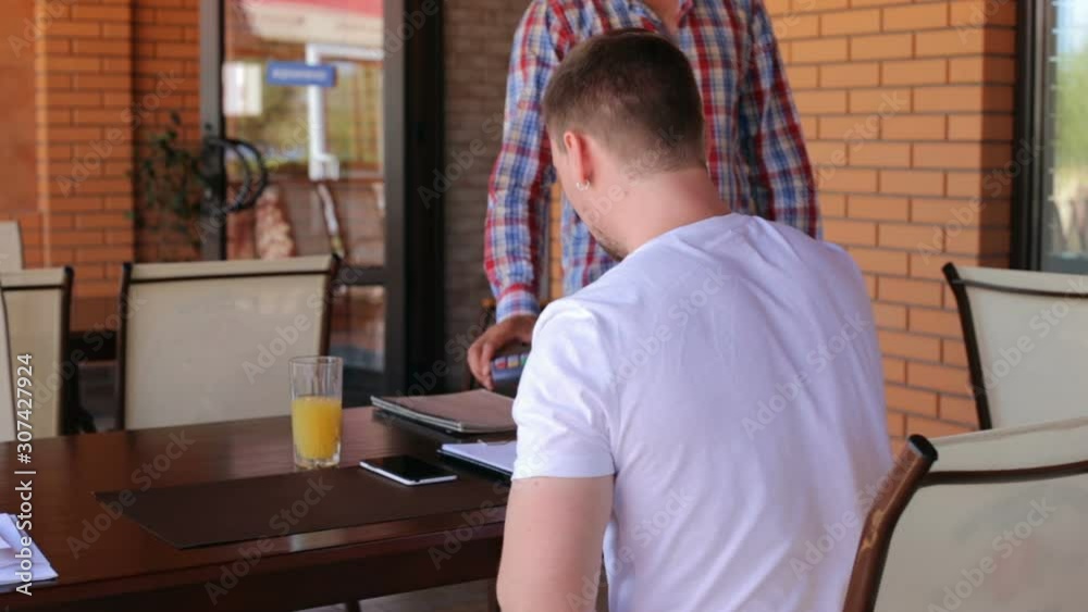Young businessman makes payment using wireless NSF system in a restaurant Young businessman makes payment using wireless NSF system in a restaurant