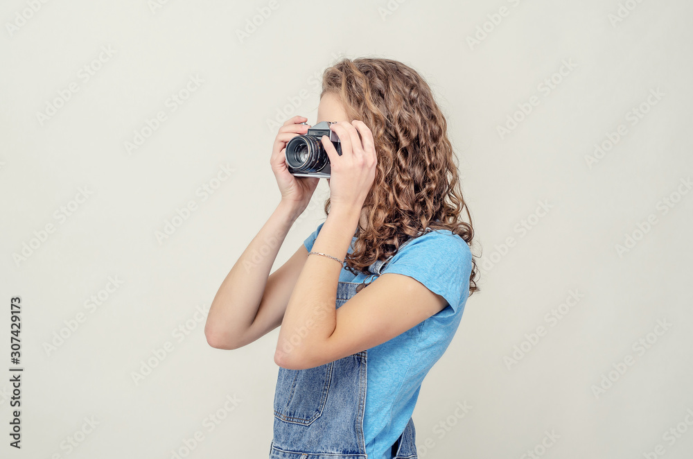 Curly brunette girl in denim overalls is holding a vintage film Curly brunette girl in denim overalls is holding a vintage film