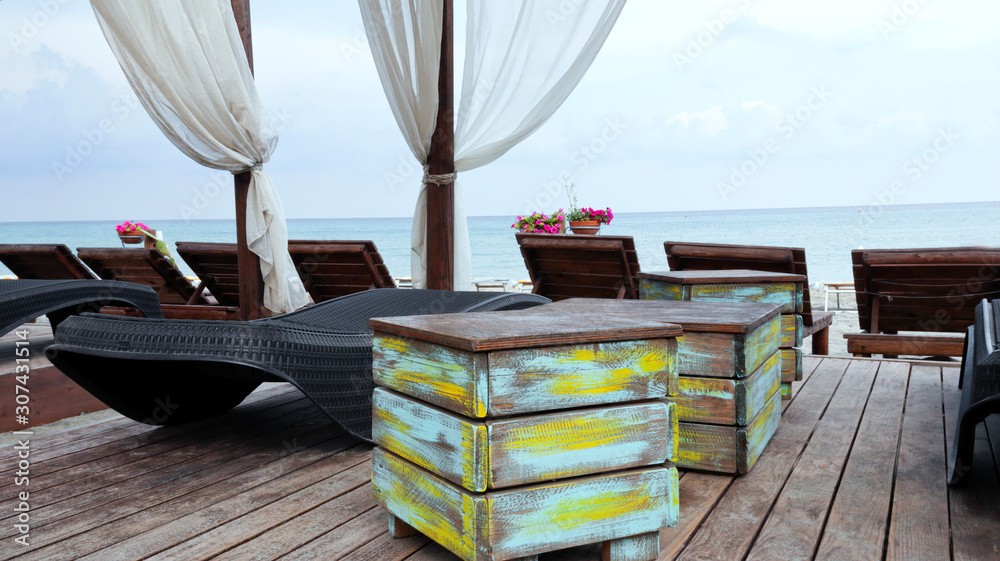 Beach loungers, rustic wooden boxes in a local bar with the sea view .