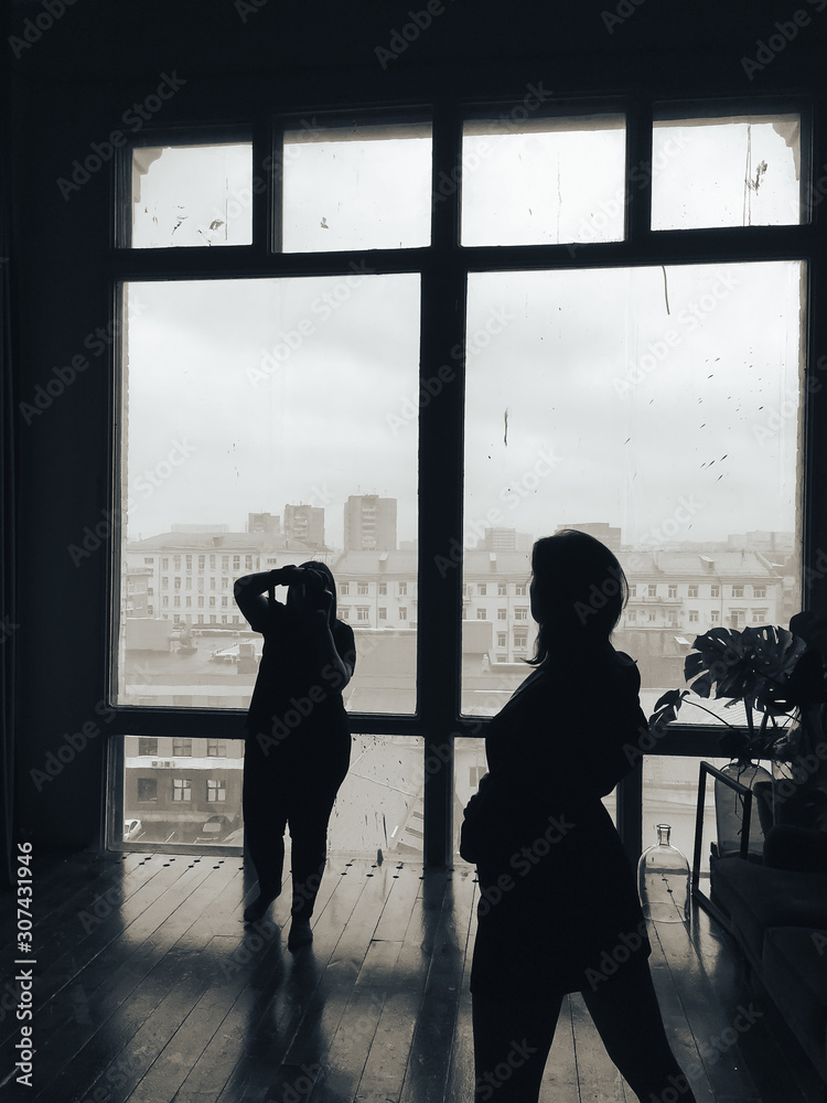 silhouette of the photographer and model in the studio on the background of huge windows