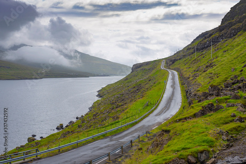 Wet road bordering a lake in the Faroe Islands