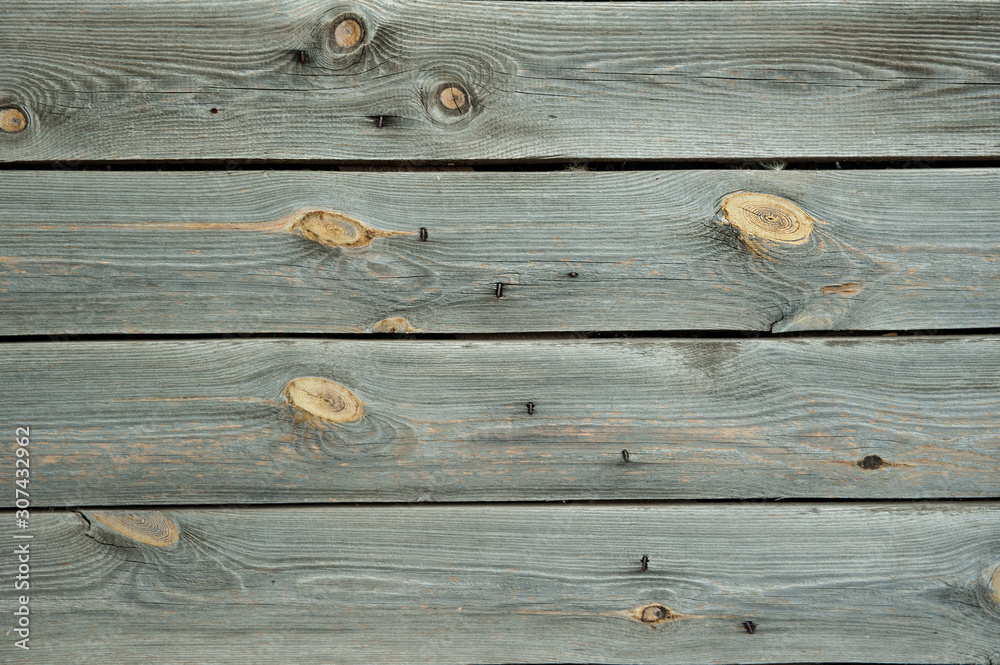 Worn old gray pine horizontal wooden boards with circles from knots and traces from nails. Abstract wooden background.