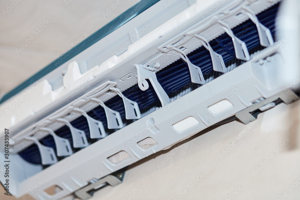 Fototapeta premium Split air conditioner closeup repair and maintenance concept. The specialist repairs the wall air conditioner. Inverter Air conditioning service
