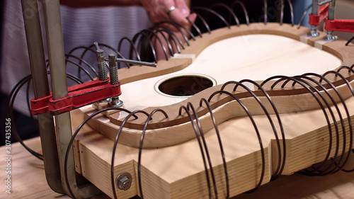 Guitar maker adding spring clamps to the guitar body photo