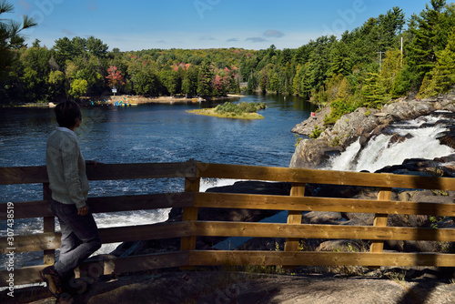 Retired woman hiker viewing North Muskoka river at High Falls Bracebridge Ontario