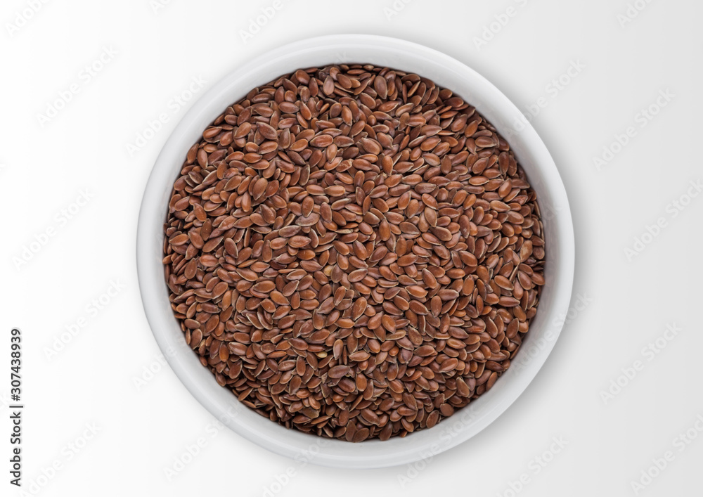 White bowl of raw natural organic linseed flax-seed on white background. White bowl of raw natural organic linseed flax-seed on white background.