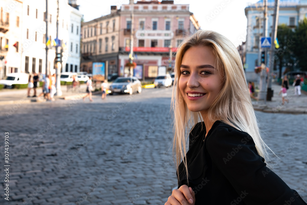 Chernivtsi, Ukraine, 25.08.2019: Young happy blonde female in black dress wanderer out sightseeing in a foreign city during weekend overseas