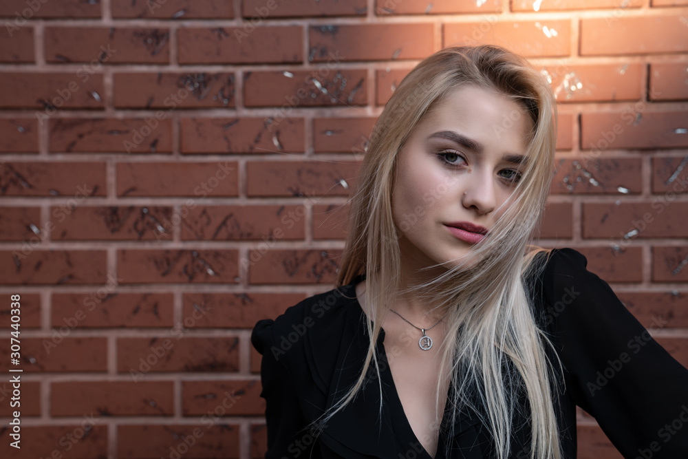 Close up portrait of a beautiful blonde girl with loose hair, red lips and blue eyes looking at the camera, red brick wall on the background Close up portrait of a beautiful blonde girl with loose hair, red lips and blue eyes looking at the camera, red brick wall on the background