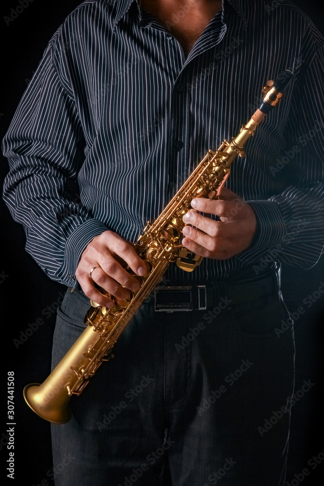 Fototapeta premium soprano saxophone in the hands of a guy on a black background