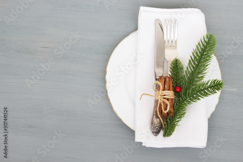 Festive table setting for Christmas dinner on a gray wooden background with place for text. The concept of winter holidays. Flat layout.