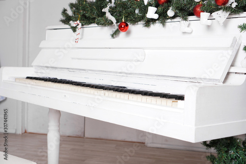 Photography Keys on white upright piano with christmas decor with red balls