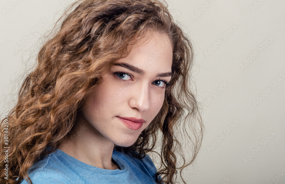 Portrait of beautiful young girl, close-up. Curly hair. Playing hair. Seductive smile Portrait of beautiful young girl, close-up. Curly hair. Playing hair. Seductive smile