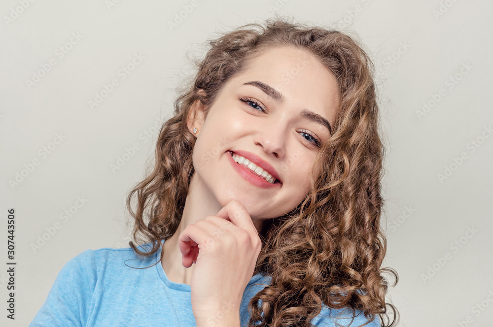 Portrait of beautiful young girl, close-up. Curly hair. Playing hair. Seductive smile Portrait of beautiful young girl, close-up. Curly hair. Playing hair. Seductive smile