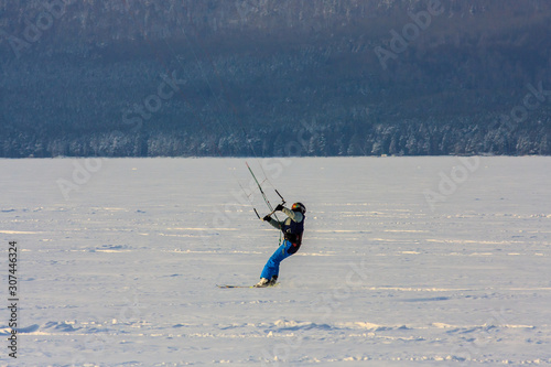 snowkiting extreme winter sport. athletes on a wild winter mountain lake in the evening at sunset ride. fresh white snow and wind. photo