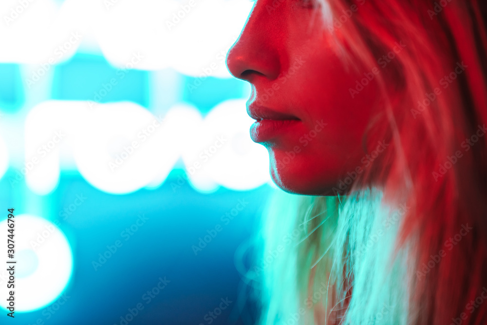 Fototapeta premium Image of young woman standing over multicolored neon text sign outdoors