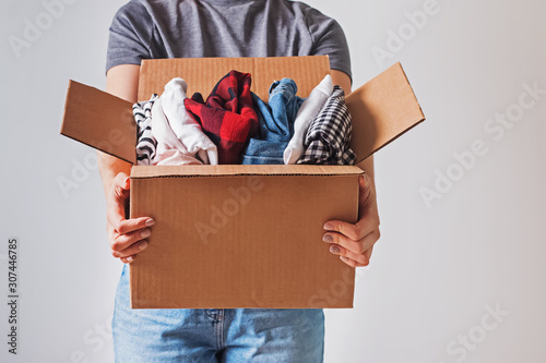Unrecognizable woman holding box with clothes in it. close-up. photo