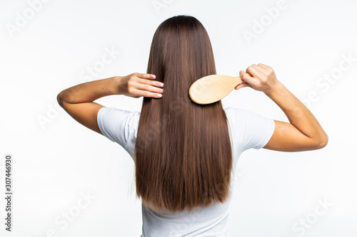 Rear view of Combing healthy long straight female hair isolated on gray background