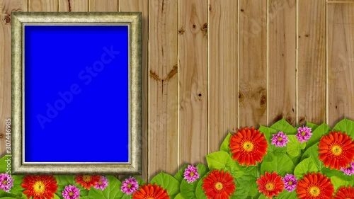 Blank picture frame with blue screen on wooden wall with colorful flowers