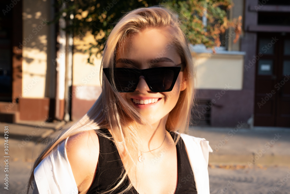 Close up portrait of attractive blonde girl with loose hair in black sunglasses, the sun's rays fall on her face Close up portrait of attractive blonde girl with loose hair in black sunglasses, the sun's rays fall on her face