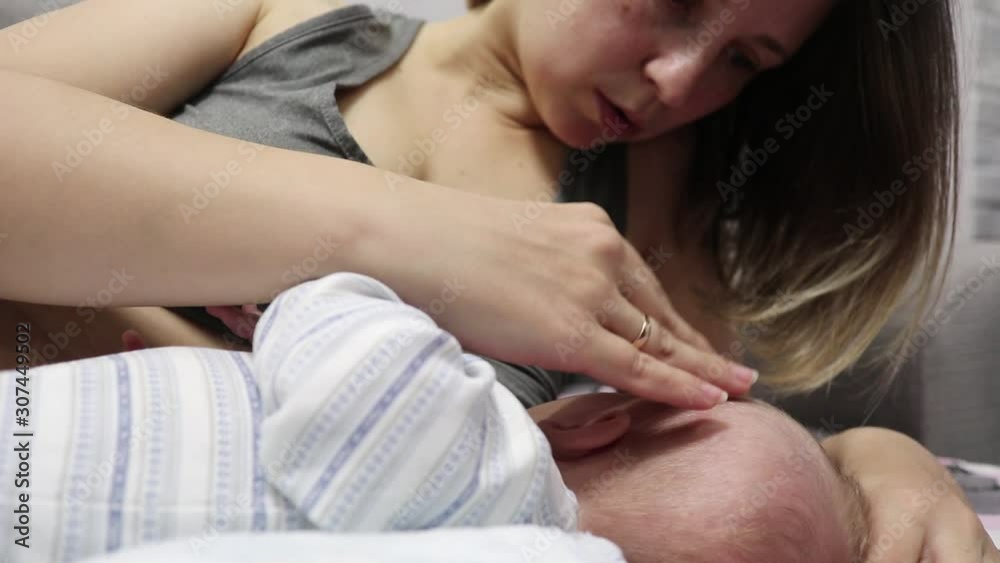 young mother breast-feeding a baby lying on the bed young mother breast-feeding a baby lying on the bed