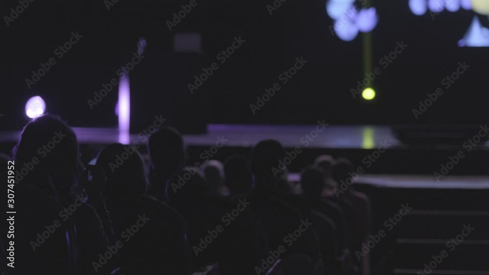 Visitors to a business forum watch a presentation on the screen