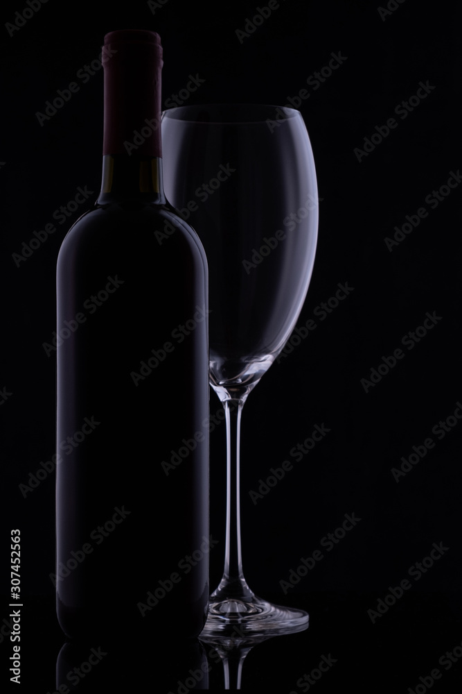 Red wine glass and a wine bottle with reflections on black background Red wine glass and a wine bottle with reflections on black background