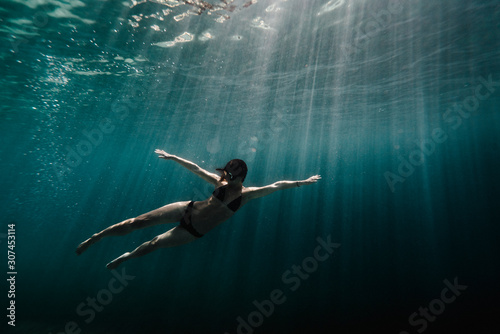Woman swimming underwater in ocean photo