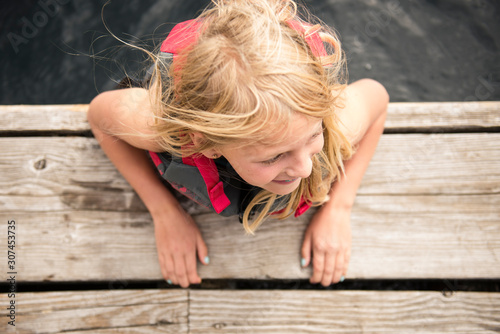 Child Smiling While Swimming at a Lake near a Dock