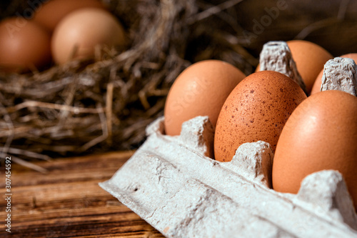 Chicken eggs in a wicker nest and in a box in a chicken coop top view. Natural organic eggs in the hay. Fresh chicken eggs. photo