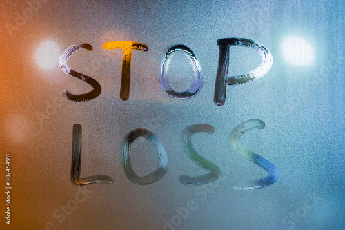 words stop loss written by hand on wet glass at morning with blurry street light background photo