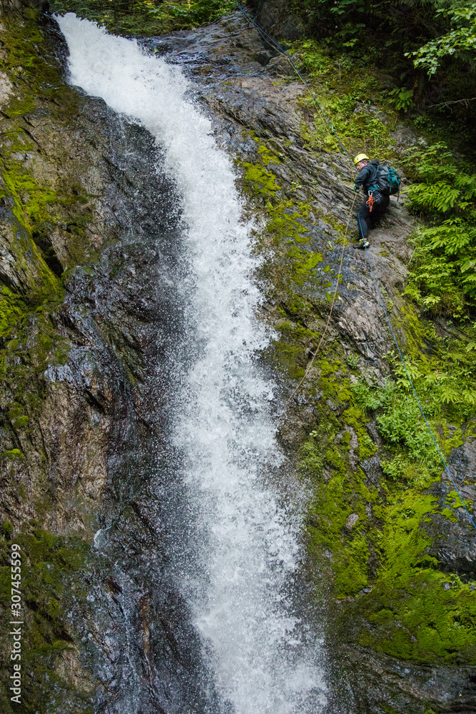 Side view of man rappelling beside waterfall in Canyon. Side view of man rappelling beside waterfall in Canyon.