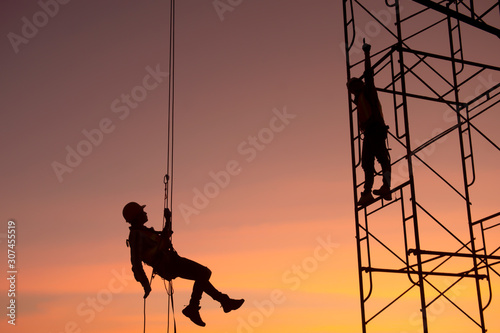 Silhouette; construction worker Climbing scaffolding In order to go up to check the work site