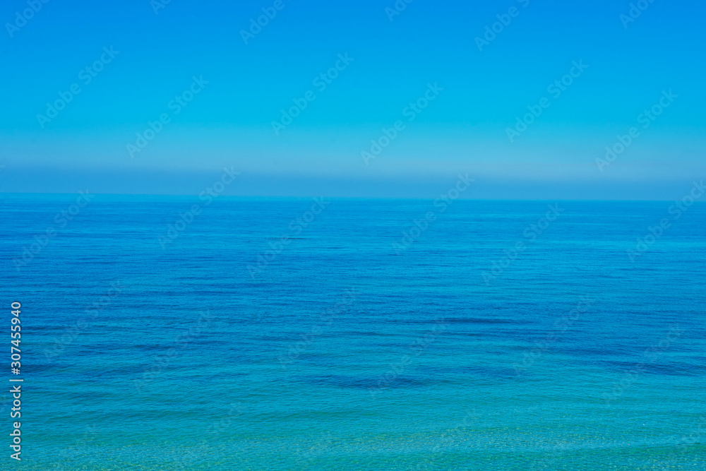 The surface of the calm sea under a clear blue sky.