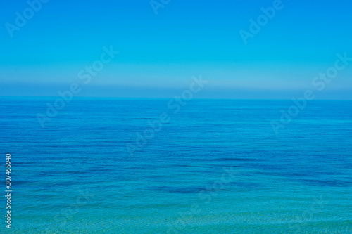 The surface of the calm sea under a clear blue sky.
