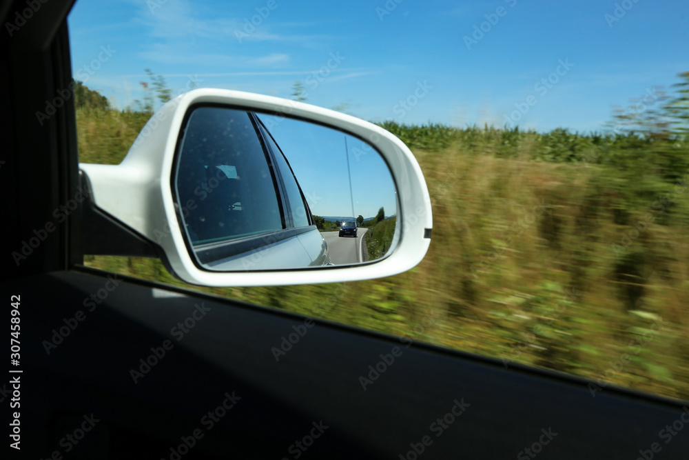 View of the road in the side mirror of the car View of the road in the side mirror of the car