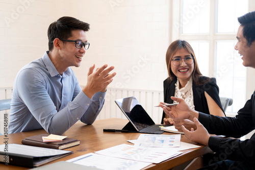 Business people laughing together while discussing paperwork dur