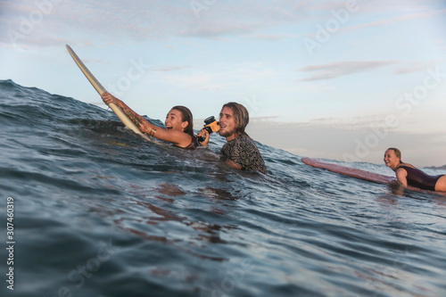 Happy friends with surfboards and camera in ocean photo