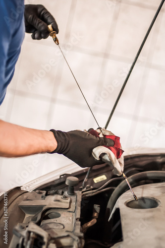 Auto mechanic repairer checking level of oil in car engine