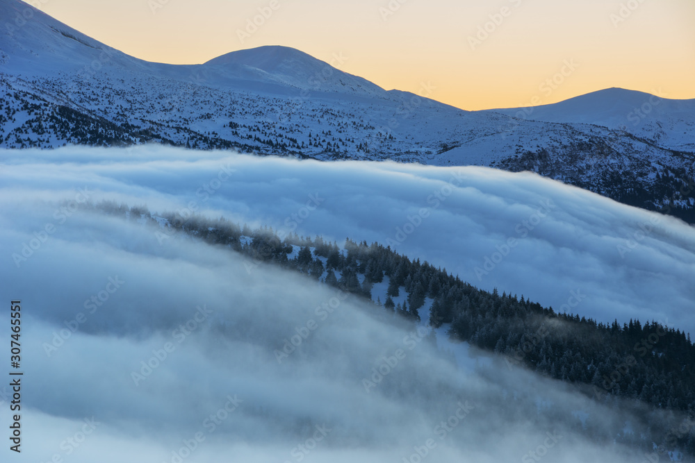 Winter camping high in the mountains, among the clouds and fog in the red tourist tent.